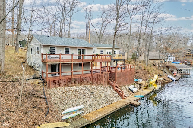 rear view of house featuring stairs, a shingled roof, and a deck with water view