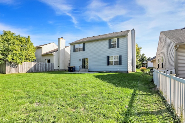 back of property with a lawn, entry steps, a chimney, and fence