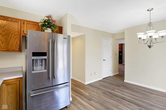 kitchen featuring brown cabinets, wood finished floors, baseboards, and stainless steel fridge with ice dispenser