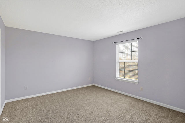 empty room featuring visible vents, carpet flooring, a textured ceiling, and baseboards