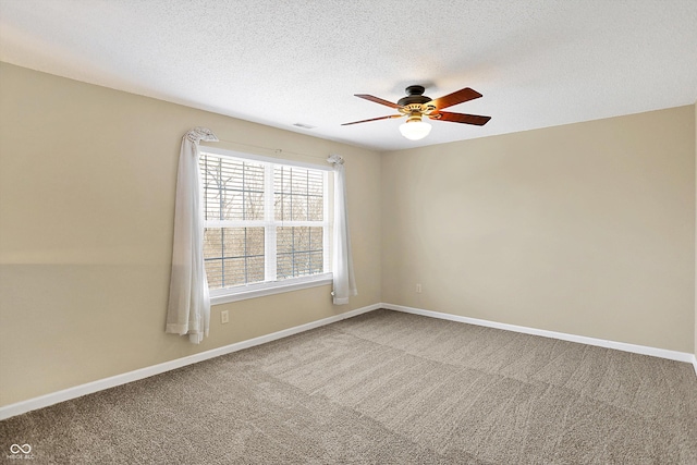 empty room featuring a ceiling fan, visible vents, baseboards, a textured ceiling, and carpet flooring