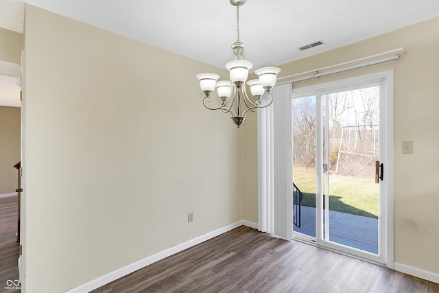 unfurnished dining area featuring dark wood-type flooring, visible vents, baseboards, and a chandelier