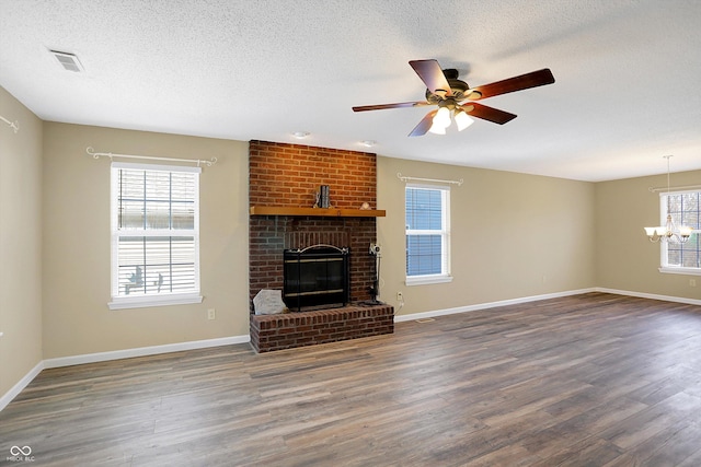 unfurnished living room with baseboards, wood finished floors, a fireplace, and ceiling fan with notable chandelier