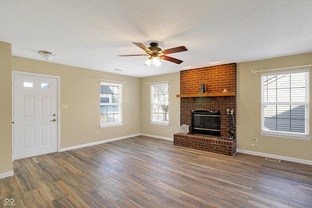 unfurnished living room with a fireplace, a textured ceiling, ceiling fan, and dark wood-style flooring