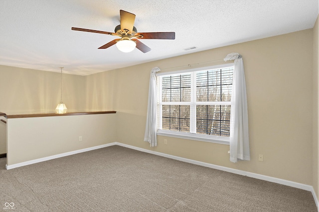 spare room featuring visible vents, carpet flooring, a textured ceiling, and baseboards