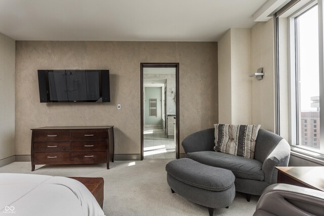 bedroom with light colored carpet, multiple windows, and ensuite bathroom