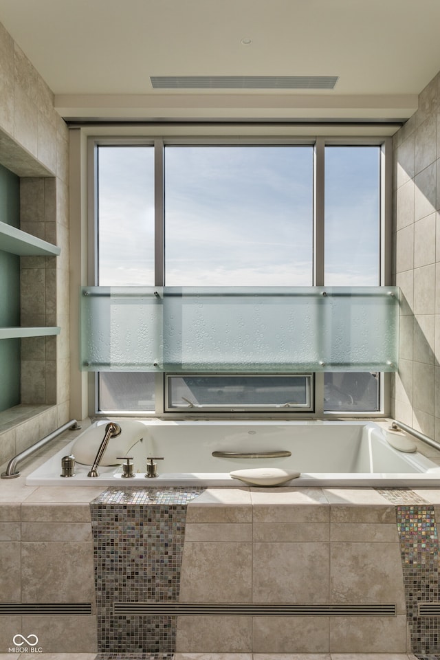 bathroom featuring tiled tub and tile walls