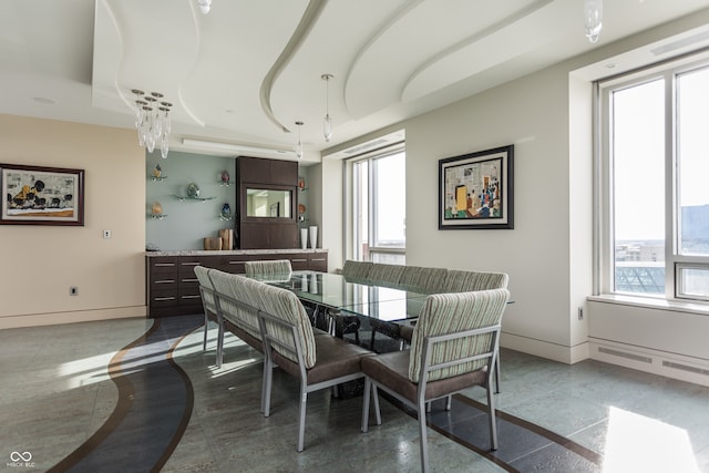 dining room featuring tile patterned flooring and a raised ceiling