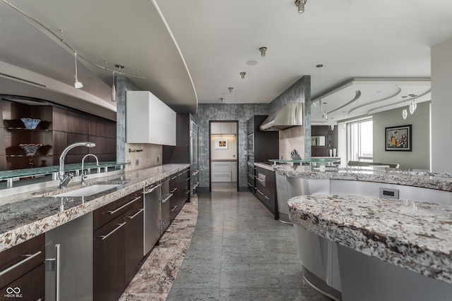 kitchen with sink, pendant lighting, dark brown cabinets, tile patterned floors, and wall chimney exhaust hood