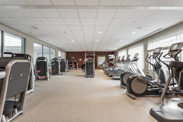 exercise room featuring a paneled ceiling and plenty of natural light