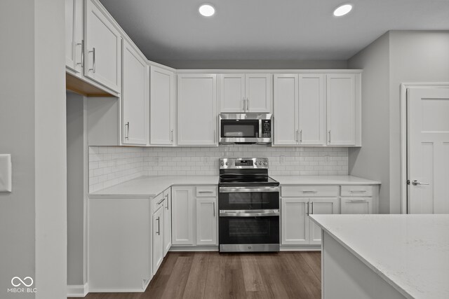 kitchen featuring tasteful backsplash, white cabinets, appliances with stainless steel finishes, and dark hardwood / wood-style flooring