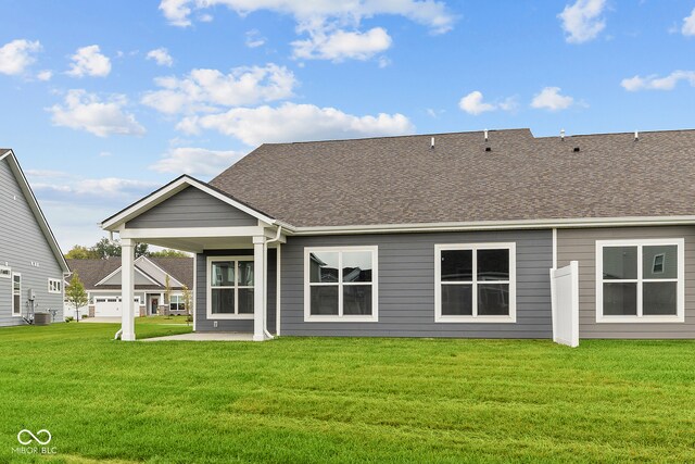 rear view of house featuring central AC unit, a garage, and a lawn