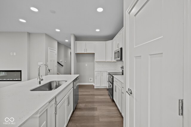 kitchen featuring light stone counters, white cabinets, sink, dark wood-type flooring, and stainless steel appliances