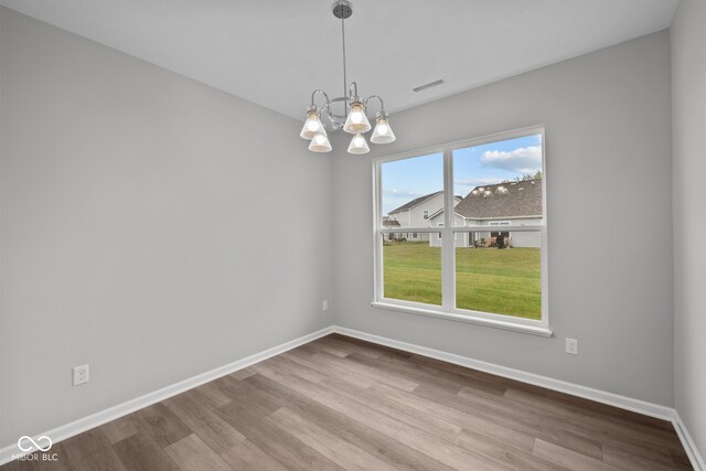 unfurnished dining area with a notable chandelier and light wood-type flooring