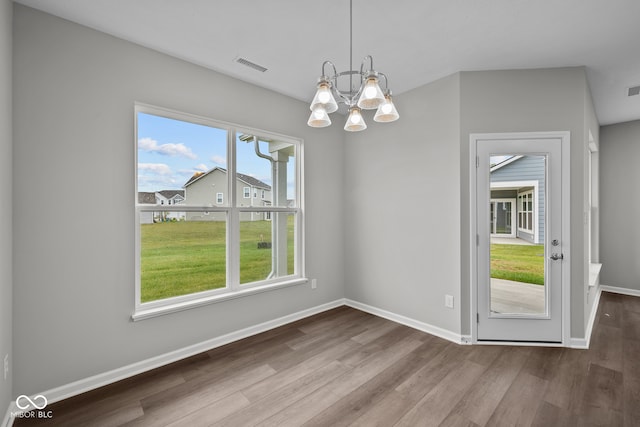 unfurnished dining area with a notable chandelier and hardwood / wood-style floors