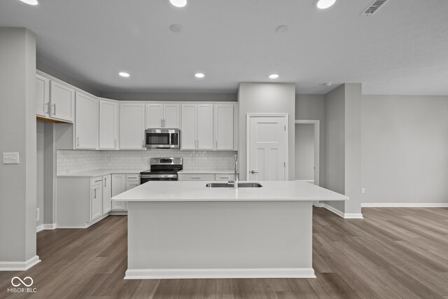 kitchen featuring white cabinets, sink, a center island with sink, stainless steel appliances, and light hardwood / wood-style floors