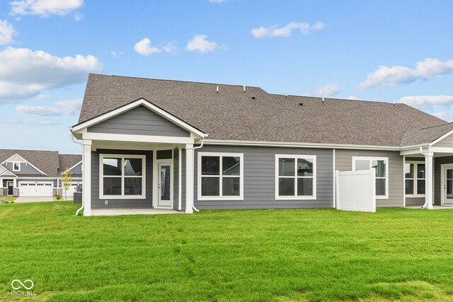 rear view of property featuring a garage and a yard