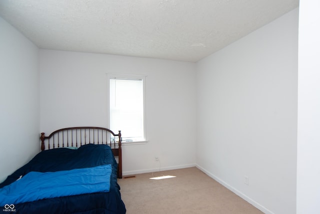 bedroom featuring light carpet and a textured ceiling