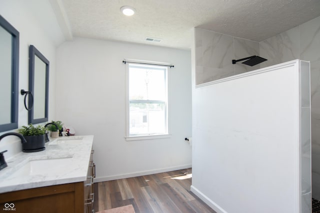 bathroom with vanity, hardwood / wood-style floors, a textured ceiling, and walk in shower