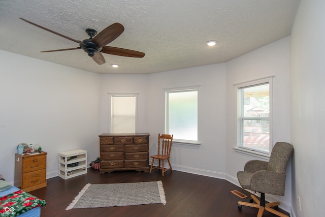 living area with ceiling fan, dark wood-type flooring, and a textured ceiling