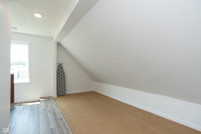 additional living space with hardwood / wood-style floors and vaulted ceiling