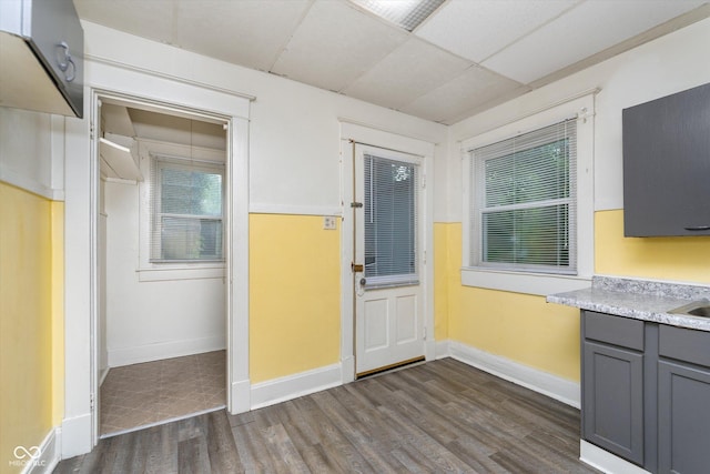 interior space featuring a drop ceiling, dark hardwood / wood-style floors, and gray cabinets