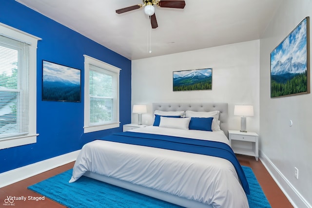 bedroom featuring ceiling fan, dark hardwood / wood-style floors, and multiple windows