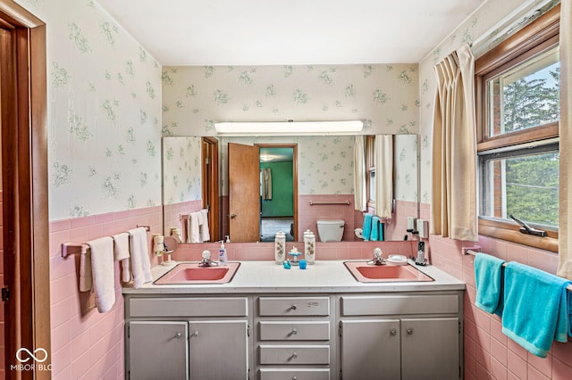 bathroom with double vanity, tile walls, and toilet