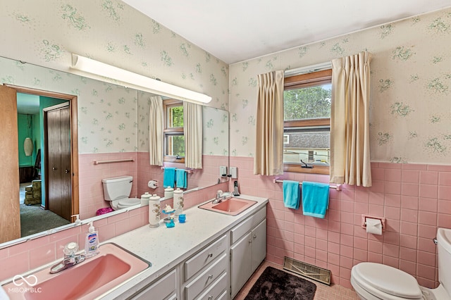 bathroom with toilet, tasteful backsplash, double sink vanity, and tile walls