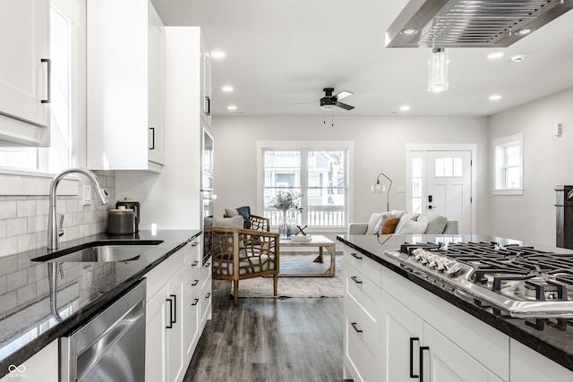 kitchen featuring dark wood-style floors, stainless steel appliances, backsplash, white cabinetry, and a sink