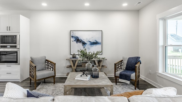 living area featuring dark wood-style floors, visible vents, and plenty of natural light