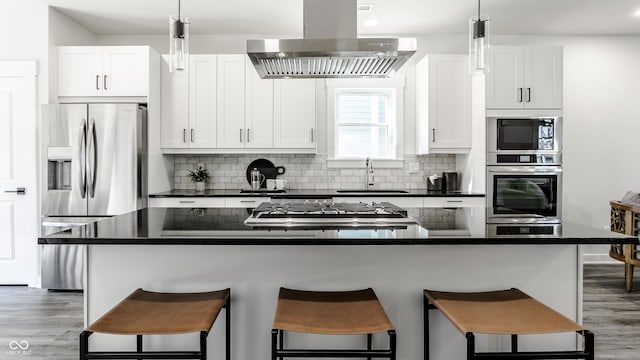 kitchen with a kitchen island, island exhaust hood, white cabinetry, and appliances with stainless steel finishes