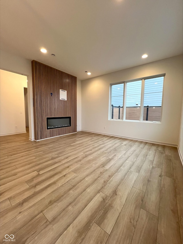 unfurnished living room featuring a large fireplace and light wood-type flooring