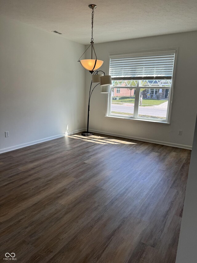 unfurnished room with a textured ceiling and dark hardwood / wood-style flooring