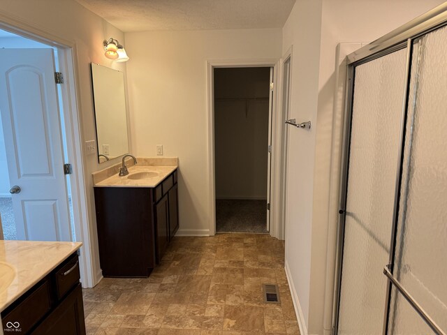 bathroom with vanity and a shower with door