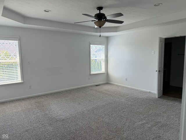 carpeted empty room featuring ceiling fan, a tray ceiling, and a textured ceiling