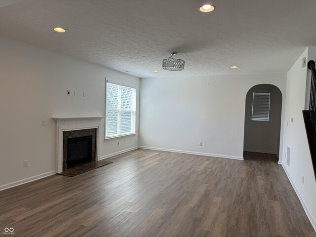 unfurnished living room featuring a premium fireplace, dark hardwood / wood-style floors, and a textured ceiling