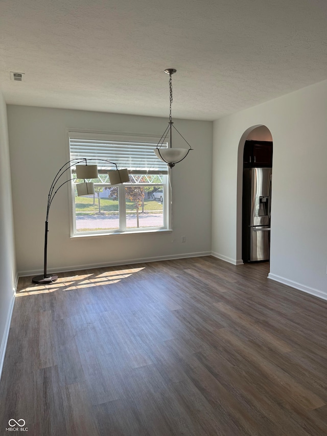 unfurnished dining area with dark hardwood / wood-style flooring and a textured ceiling