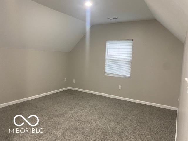 bonus room with lofted ceiling and dark carpet