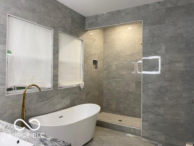 bathroom with plus walk in shower, tile patterned flooring, and tile walls