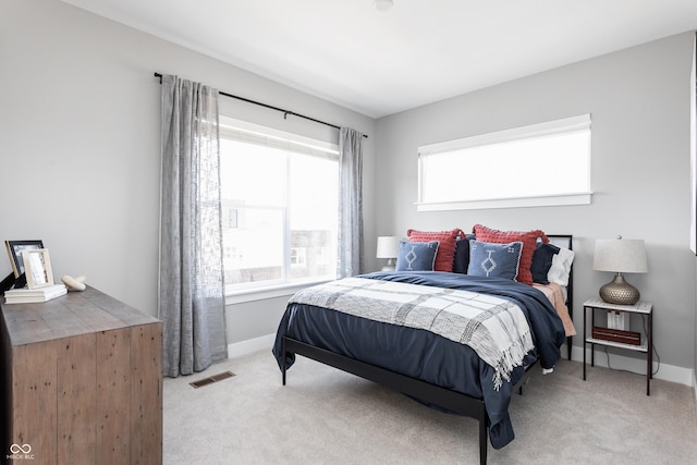 bedroom with multiple windows and light colored carpet