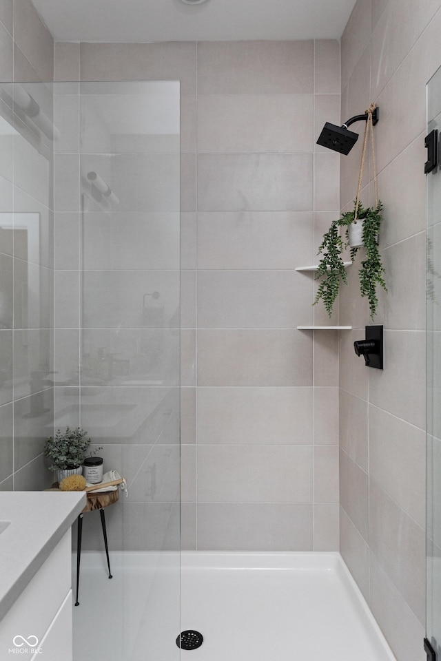 bathroom with a tile shower and vanity