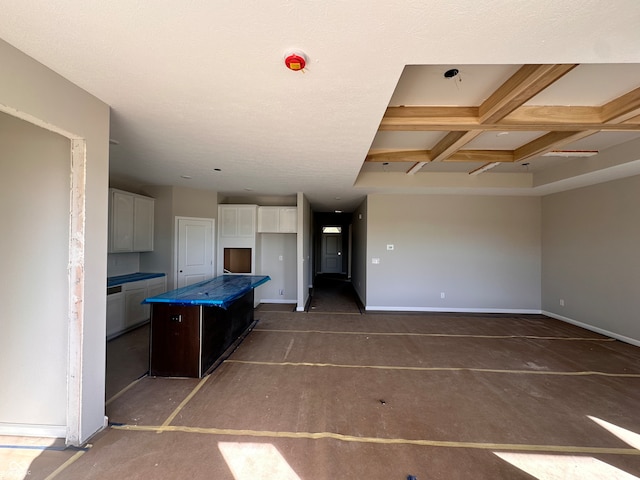 kitchen with white cabinets, beam ceiling, a kitchen island, and coffered ceiling