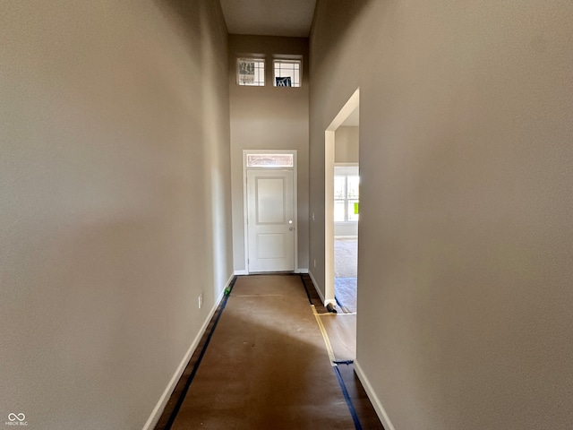 hallway featuring a healthy amount of sunlight and a towering ceiling