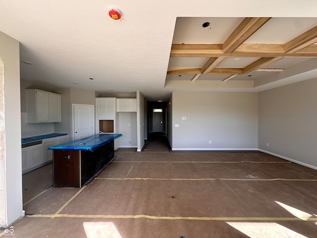 kitchen with white cabinetry, beamed ceiling, a kitchen island, and coffered ceiling