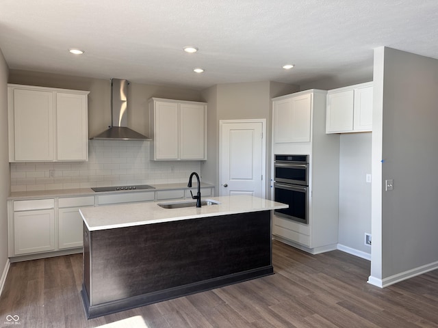 kitchen with sink, black electric cooktop, dark wood-type flooring, and wall chimney range hood