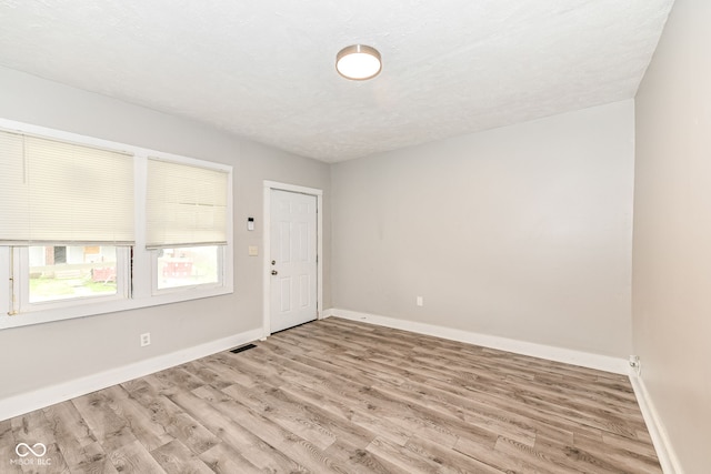 spare room with light wood-type flooring and a textured ceiling