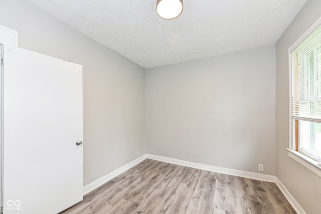 spare room with light hardwood / wood-style floors and a textured ceiling