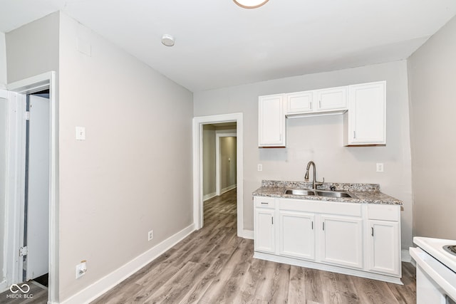 kitchen featuring white cabinets, light stone countertops, sink, and range