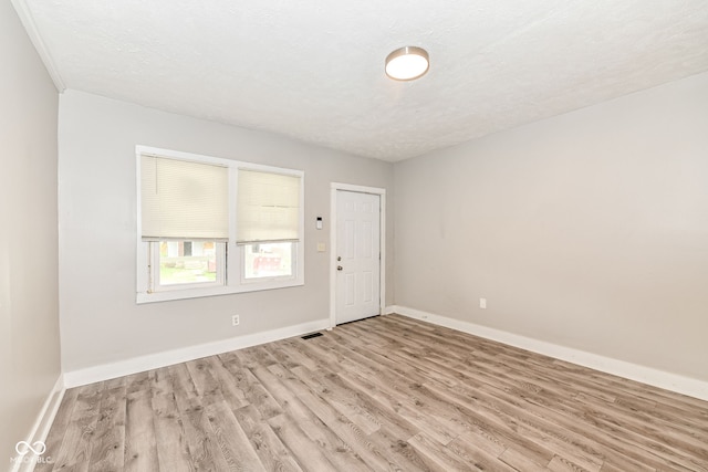 unfurnished room with a textured ceiling and light hardwood / wood-style flooring